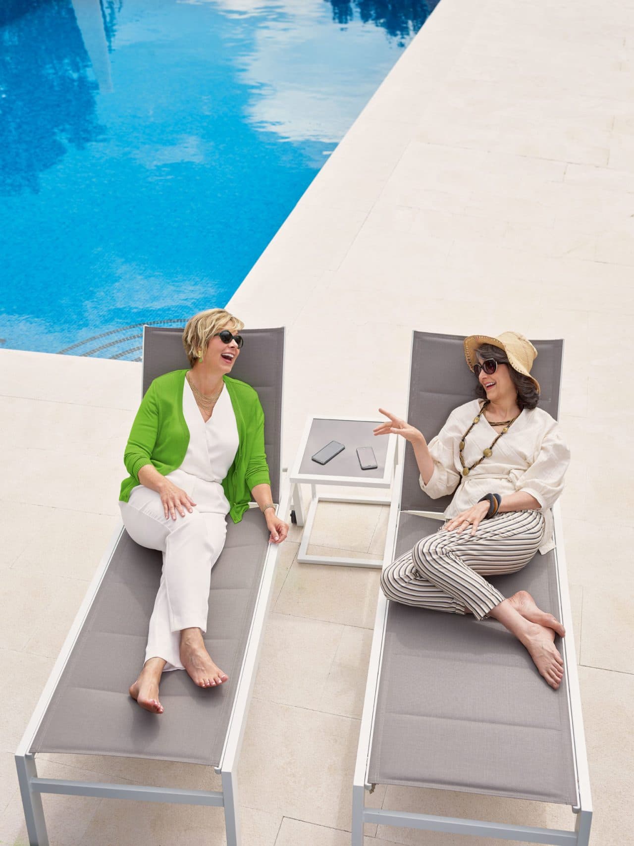 Photo of two women talking and smiling next to a pool