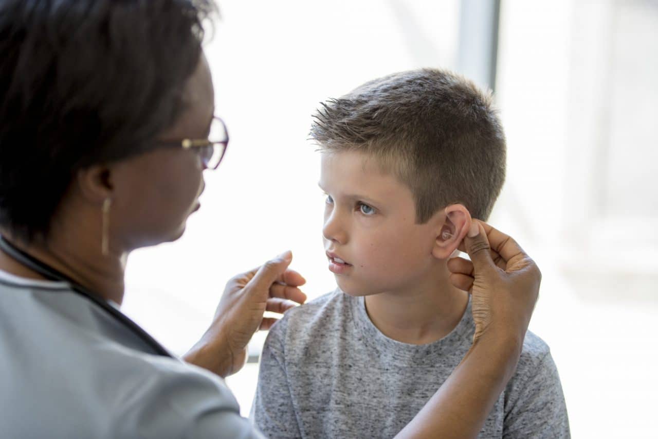 Photo of a practitioner fitting a child with a hearing device