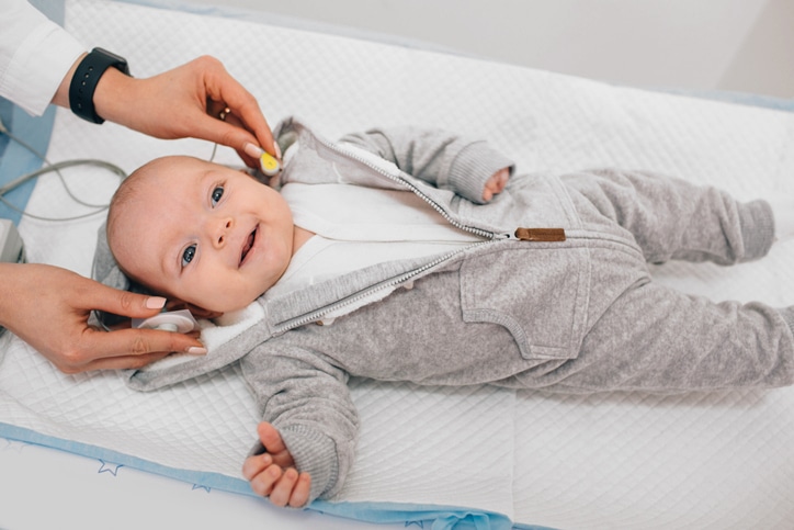 Photo of a smiling baby having hearing instruments placed around their head