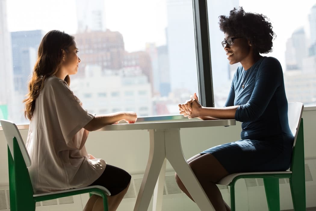 Two women having a conversation at a table.