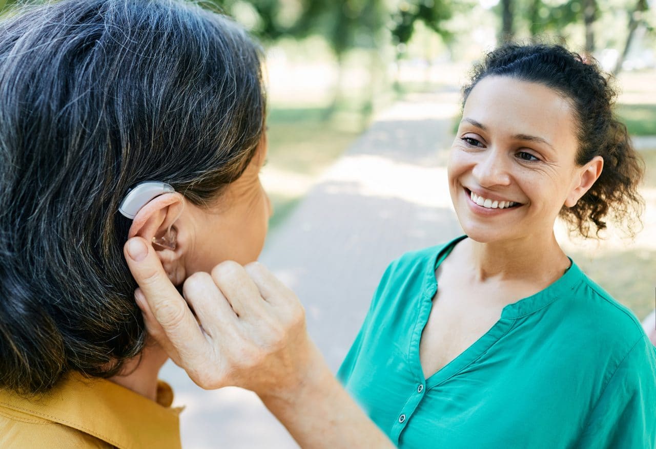 Woman with hearing aid having a conversation with her friend outside.