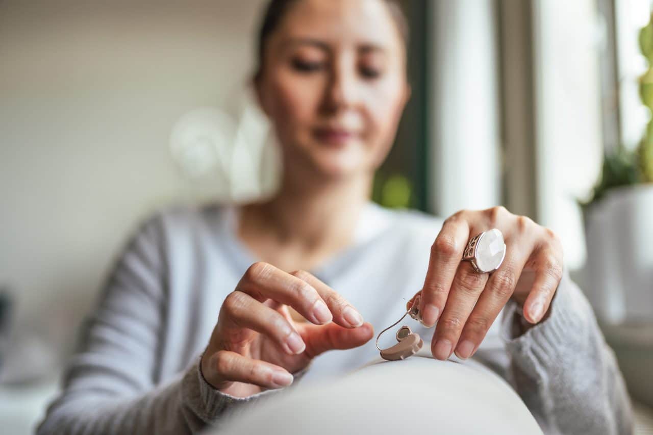 Young Adult Woman inserting battery into the Hearing Aid