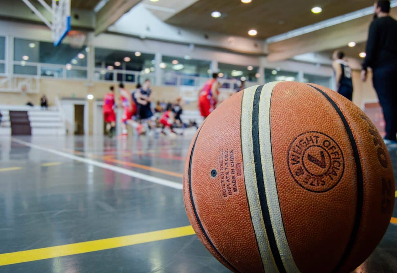 Closeup of a basketball with people playing in the background.
