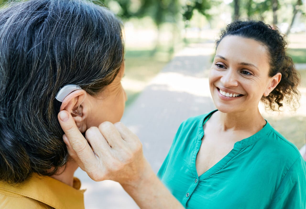 Senior woman with a hearing aid chatting with a friend.