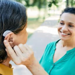 Senior woman with a hearing aid chatting with a friend.