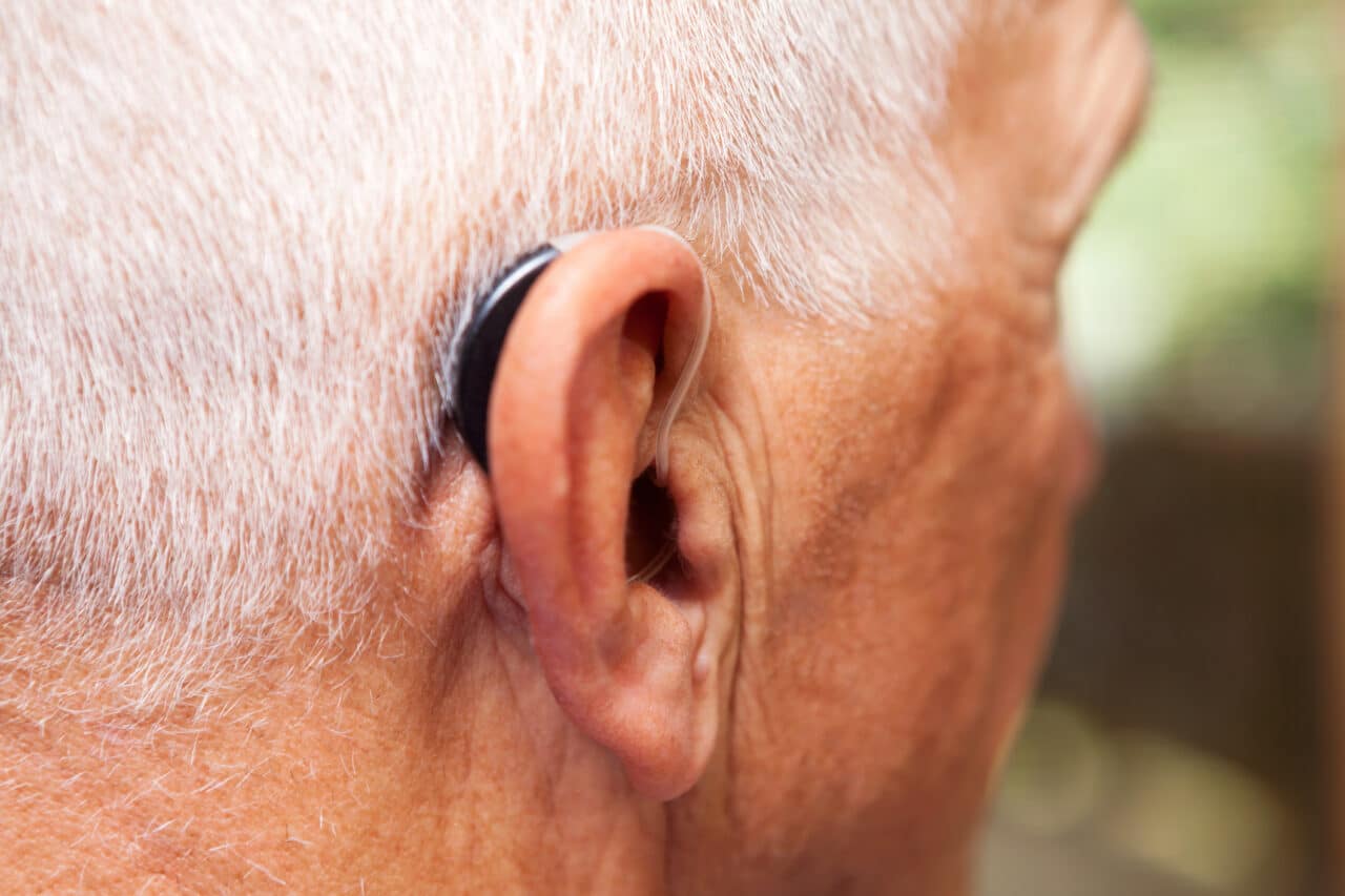 Close up of a senior man with a behind-the-ear hearing aid.