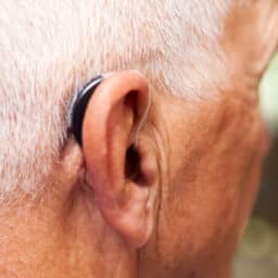 Close up of a senior man with a behind-the-ear hearing aid.