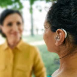 Woman wears hearing aid in park