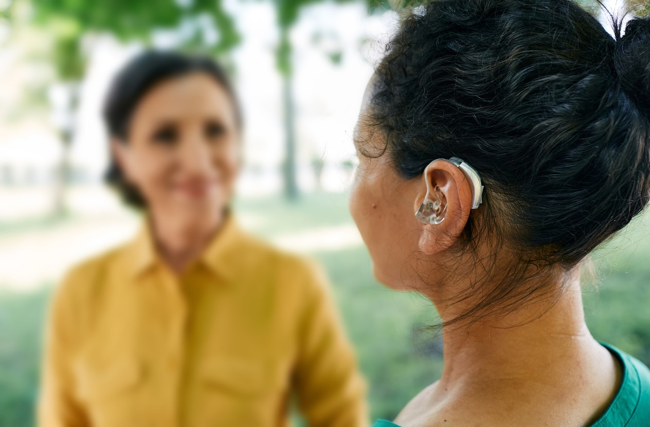 Woman wears hearing aids in the park