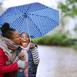 Mother and daughter smiling under an umbrella