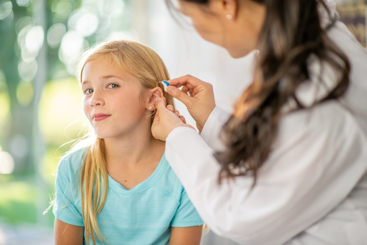 Young girl getting a new pair of hearing aids.