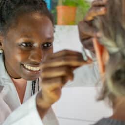 Happy doctor fitting a woman with a hearing aid