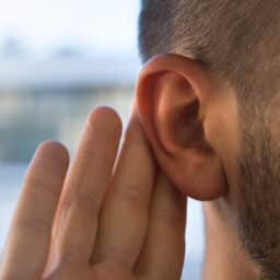 Man with a hand to his ear closeup.