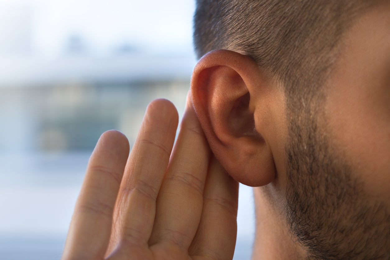 Man with a hand to his ear closeup.