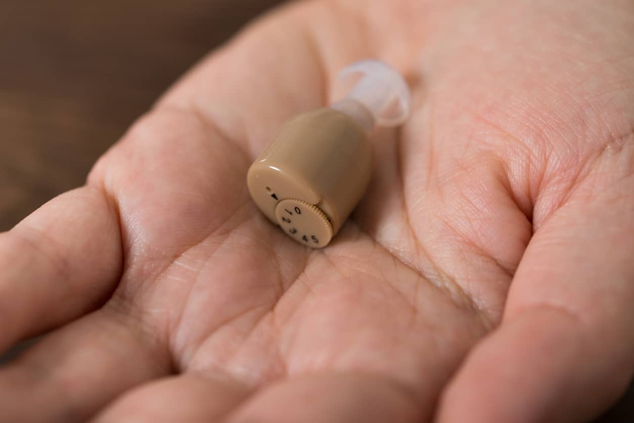 Hand holding an in-the-canal hearing aid.