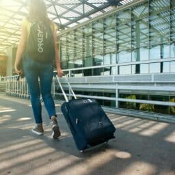 Woman walking through an airport with a suitcase.