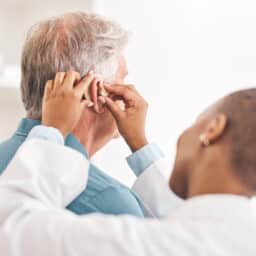 Audiologist fits their patient with a new hearing aid.