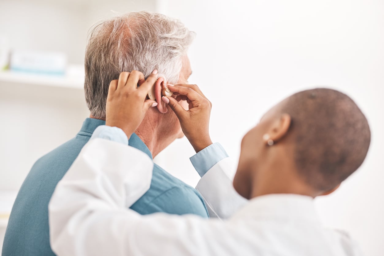 Audiologist fits their patient with a new hearing aid.